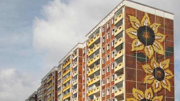 Ein Wohnhaus mit einem großen Sonnenblumen-Mosaik an der Fassade.