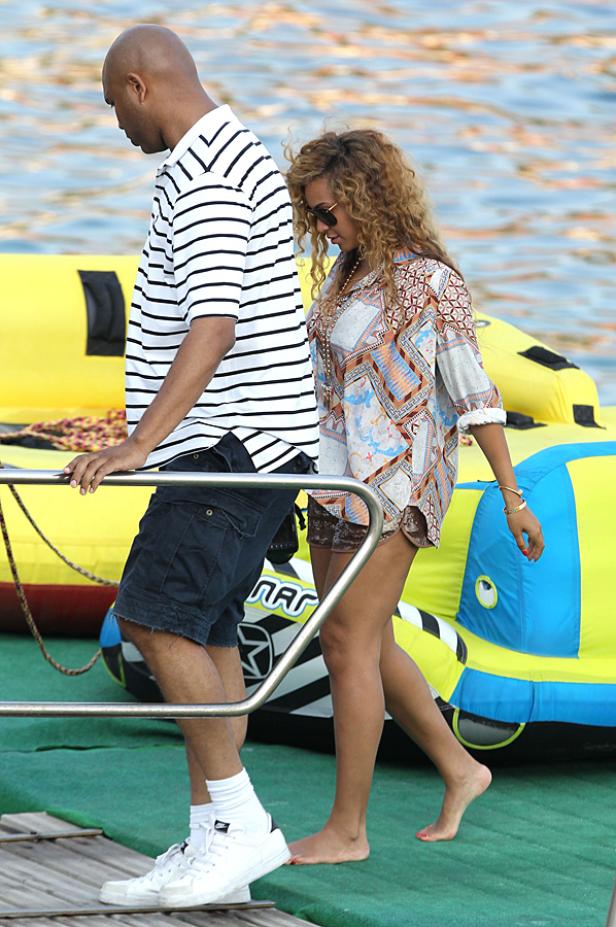Beyoncé und ein Mann gehen barfuß an einem gelben Schlauchboot vorbei.