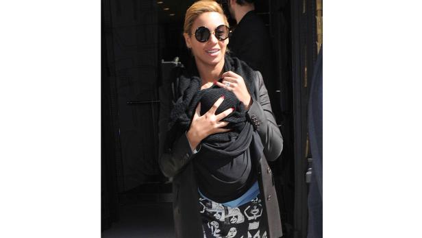 Beyoncé trägt ihr Kind in einer Trage vor dem Bauch.