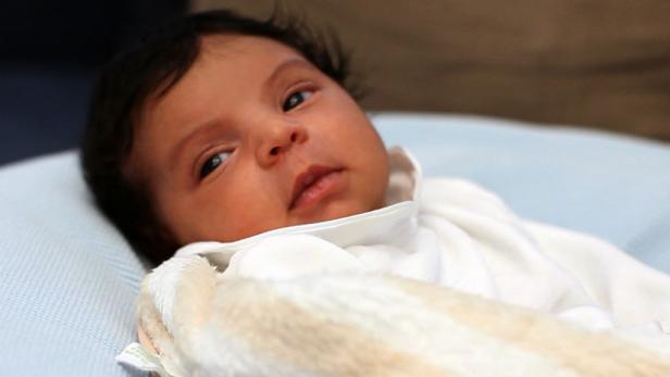 Ein neugeborenes Baby liegt auf einer hellblauen Decke.