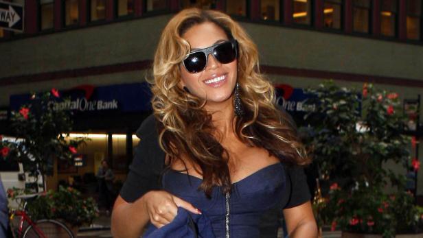 Beyoncé trägt eine Sonnenbrille und lächelt vor einer Capital One Bank.