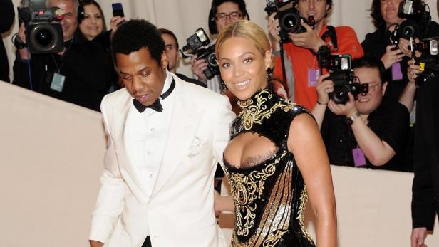 Beyoncé und Jay-Z posieren auf dem roten Teppich vor einer Gruppe von Fotografen.