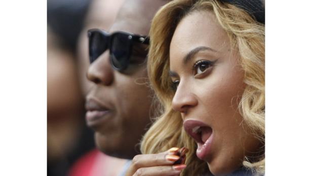 Beyoncé isst etwas, während Jay-Z im Hintergrund steht.