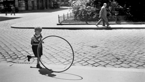 Ein Junge spielt mit einem Hula-Hoop-Reifen auf einer gepflasterten Straße.