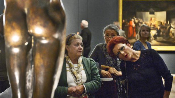 Besucherinnen betrachten eine Bronzeskulptur in einer Kunstausstellung.