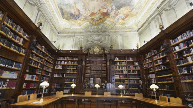 Ein Lesesaal mit hohen Bücherregalen und einem Deckenfresko.