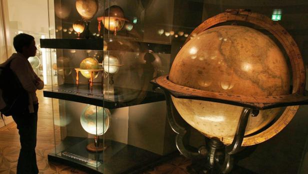 Eine Besucherin betrachtet eine Ausstellung von Globen in einem Museum.