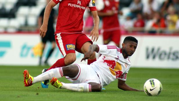 Ein Fußballspieler liegt auf dem Rasen, während ein anderer Spieler sich nähert.