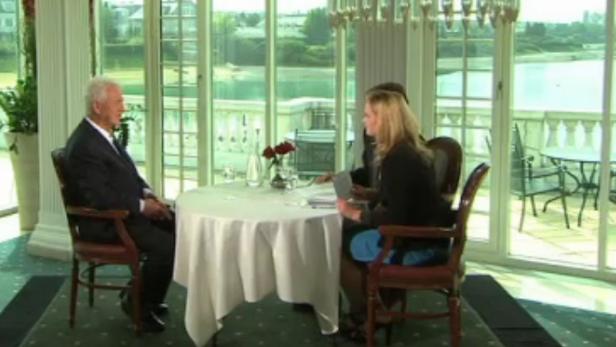 Ein Mann und eine Frau sitzen an einem Tisch in einem eleganten Restaurant mit Seeblick.