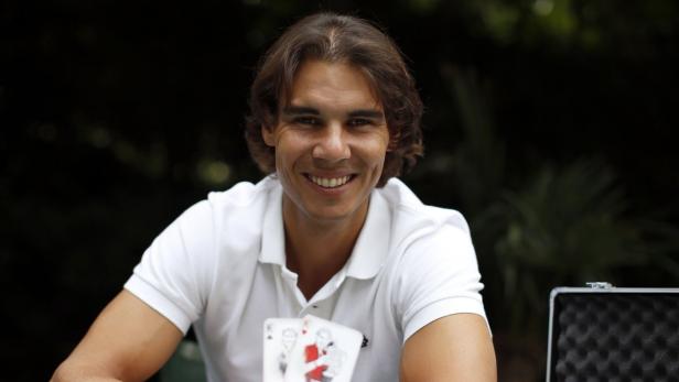 Rafael Nadal hält ein Ass-König-Blatt vor einem Pokerkoffer.