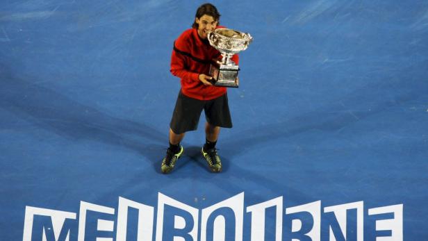 Rafael Nadal hält eine Trophäe auf einem Tennisplatz in Melbourne.
