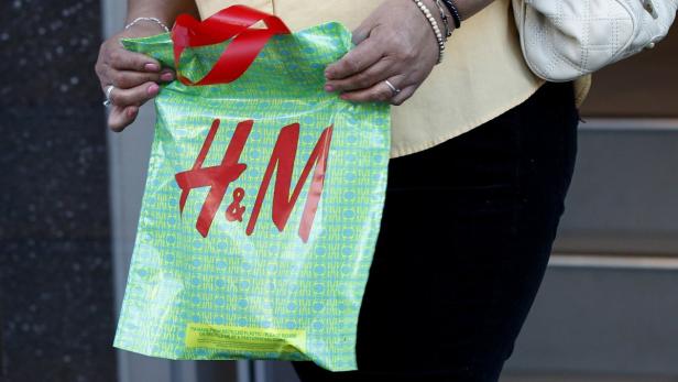 Eine Person hält eine grüne H&M-Einkaufstasche mit rotem Logo.