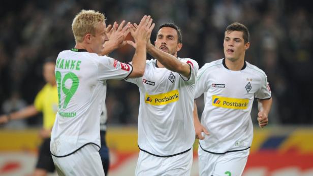 Drei Fußballspieler von Borussia Mönchengladbach feiern auf dem Spielfeld.