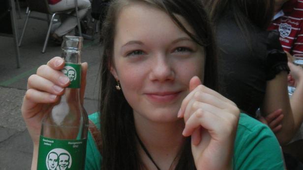 Eine junge Frau hält eine Flasche „Honigmelone“ Limonade in der Hand.