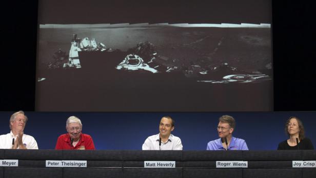 Fünf Personen sitzen vor einer Leinwand mit einer Panoramaaufnahme der Mondoberfläche.