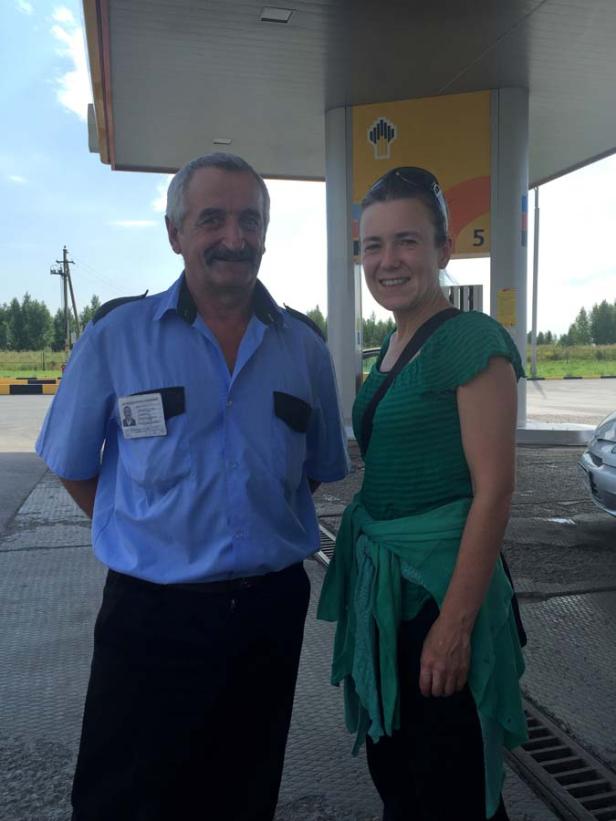 Eine Frau posiert mit einem Tankstellenmitarbeiter für ein Foto.