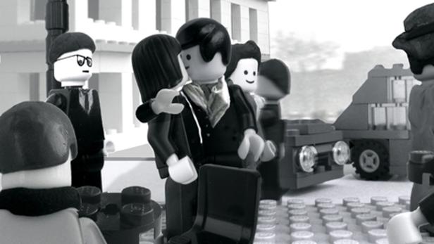 Eine Schwarzweißaufnahme von Lego-Figuren, die eine Straßenszene darstellen.