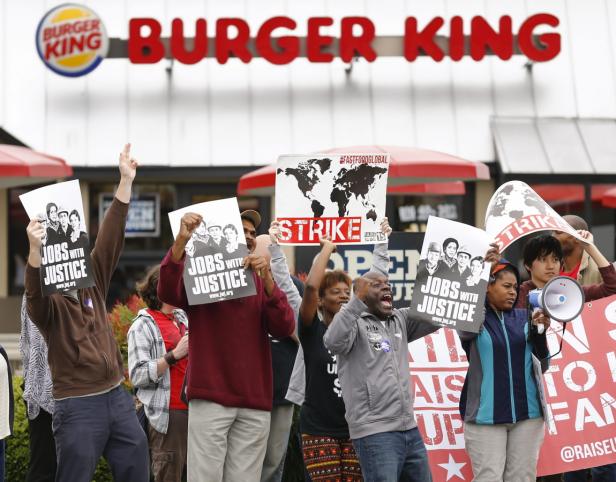 Eine Gruppe von Menschen demonstriert vor einem Burger King Restaurant für bessere Arbeitsbedingungen.