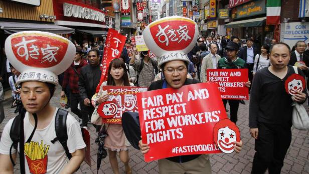 Demonstranten in Tokio fordern faire Bezahlung und Respekt für Arbeiter im Fast-Food-Sektor.