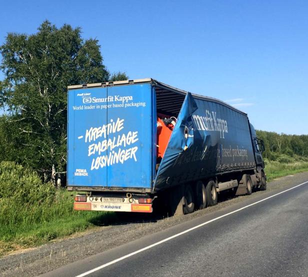 Ein Lastwagen von Smurfit Kappa mit beschädigter Plane steht am Straßenrand.