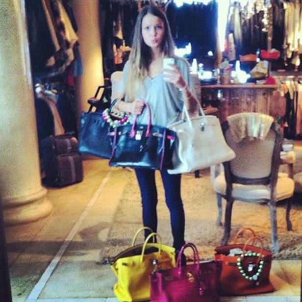 Eine Frau macht ein Selfie mit mehreren Handtaschen in einem Geschäft.