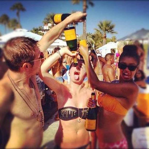 Auf einer Party gießen zwei Personen einer Frau Champagner in den Mund.