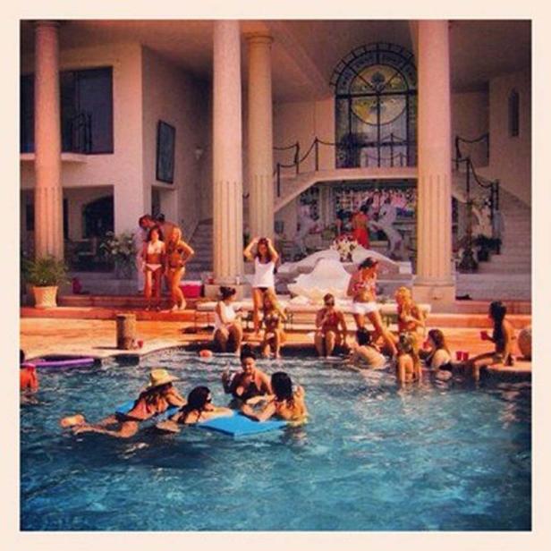 Eine Gruppe von Menschen genießt eine Poolparty in einem luxuriösen Anwesen.