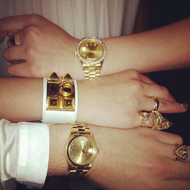 Mehrere Hände zeigen goldene Uhren, Ringe und ein weißes Armband.