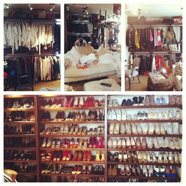 Ein begehbarer Kleiderschrank mit Kleidung, Schuhen und einer Couch.