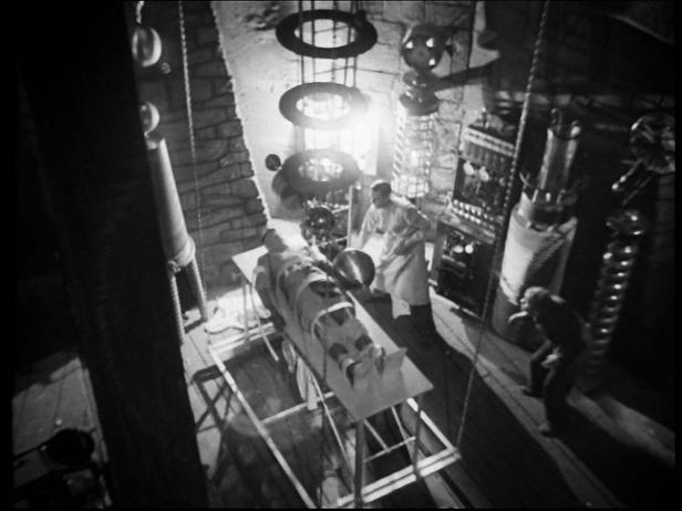 Ein Mann in einem Laboratorium, der über einer auf einem Tisch liegenden Person steht.