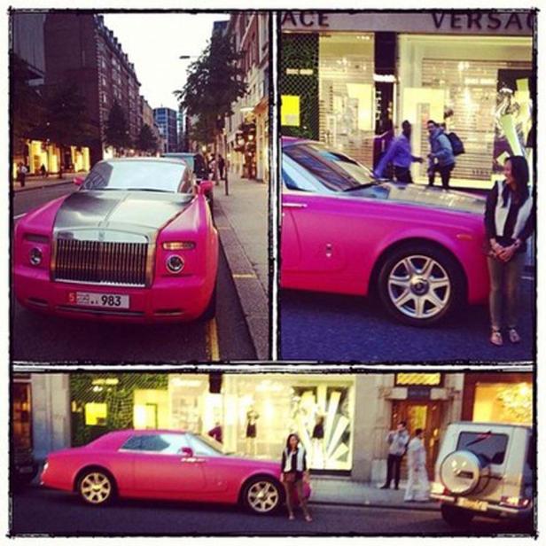 Ein pinkfarbener Rolls-Royce parkt vor einem Versace-Geschäft in einer Stadt.