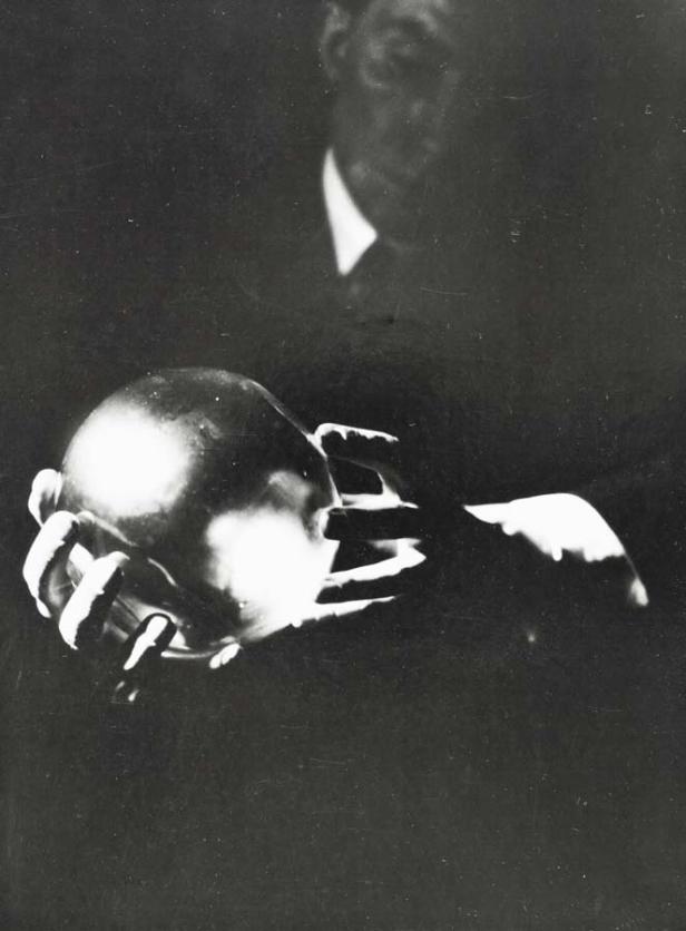 Ein Mann hält eine glänzende Kugel in seinen Händen.