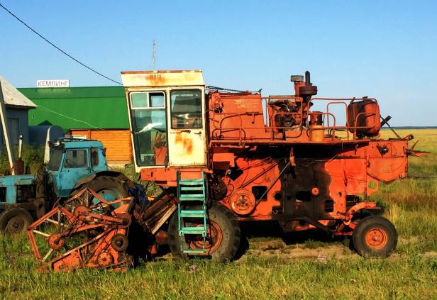 Ein orangefarbener Mähdrescher steht auf einem Feld.