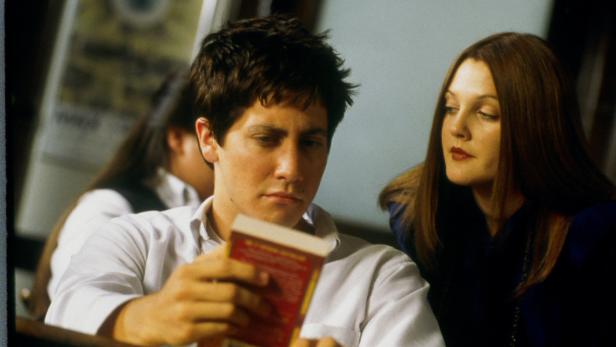 Jake Gyllenhaal liest ein Buch, während Drew Barrymore daneben sitzt.