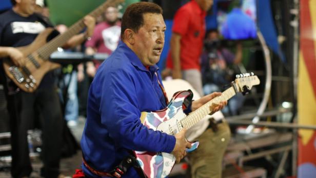 Hugo Chávez spielt Gitarre mit einer Band im Hintergrund.