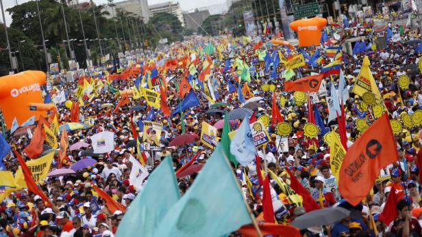 Eine große Menschenmenge demonstriert mit Fahnen und Transparenten in einer Stadt.