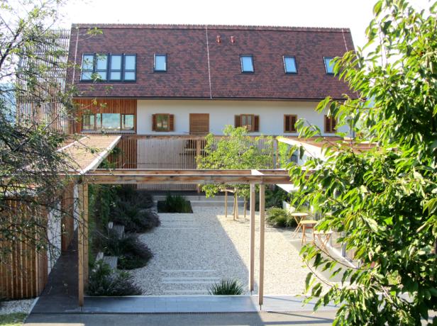 Ein modernes Haus mit einem Kiesgarten und einer hölzernen Pergola.