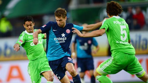 Drei Fußballspieler kämpfen um den Ball während eines Spiels.