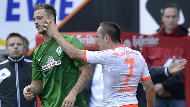 Ein Fußballspieler berührt das Gesicht eines anderen Spielers während eines Spiels.