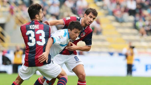 Drei Fußballspieler kämpfen um den Ball während eines Spiels.