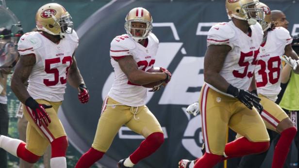 Mehrere Footballspieler der San Francisco 49ers laufen auf dem Feld.