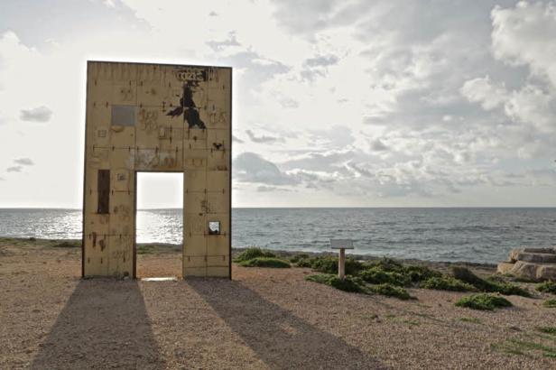 Eine Installation in Form eines Tores steht an einer Küste.