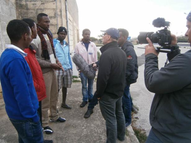 Eine Gruppe von Männern wird von einem Kamerateam gefilmt.