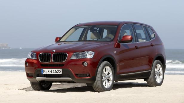 Ein roter BMW X3 steht am Strand.