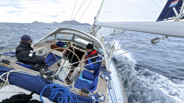 Zwei Personen segeln eine Yacht auf dem offenen Meer.