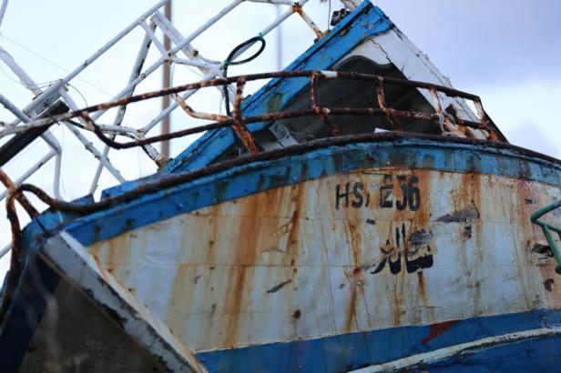 Detailansicht eines alten, verrosteten Fischerbootes mit arabischer Schrift.