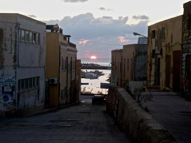 Sonnenuntergang über dem Meer, gesehen durch eine Gasse in einer Stadt.