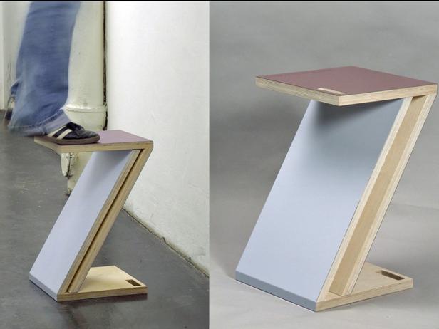 Ein Z-förmiger Hocker aus Holz und grauem Kunststoff, der als Trittstufe dient.