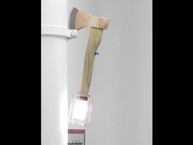 Eine Axt ist an einer Wand befestigt und dient als Lampe.