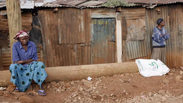 Zwei Frauen vor einer Hütte aus Wellblech in einem Slum.